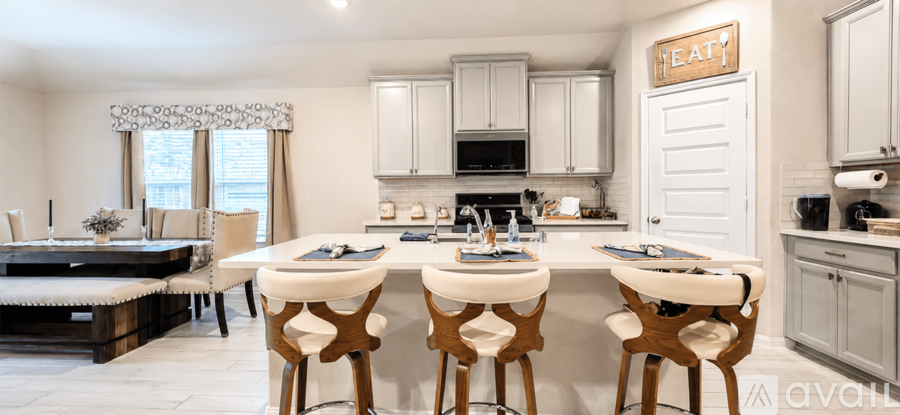 A kitchen with a breakfast bar and white chairs.