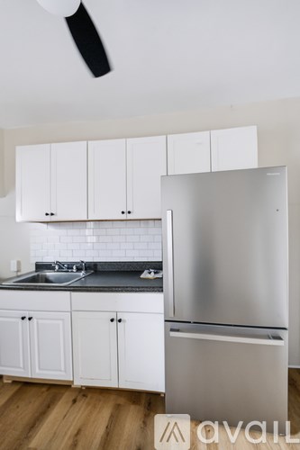 A kitchen with white cabinets and a stainless steel refrigerator.