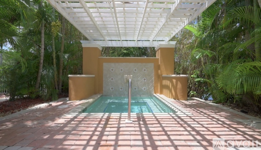 A pool with a waterfall in the middle of a patio.