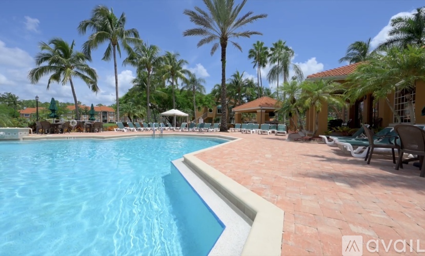 A large swimming pool surrounded by palm trees and a few buildings.