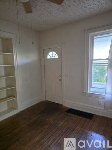 A room with a door, a window, and a ceiling fan.