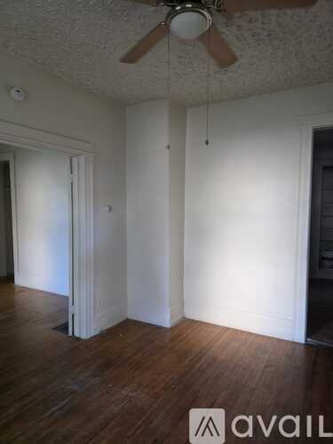 A room with a ceiling fan and wood flooring.