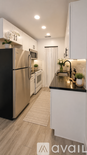 A modern kitchen with a black refrigerator and white cabinets.