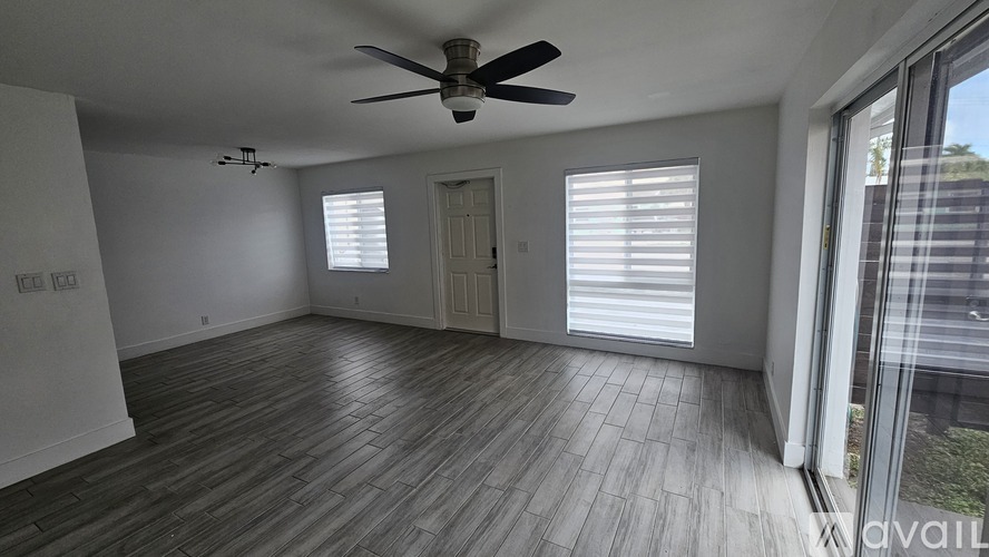 A spacious room with a ceiling fan and sliding glass doors.