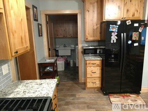 A kitchen with wooden cabinets and a black fridge.