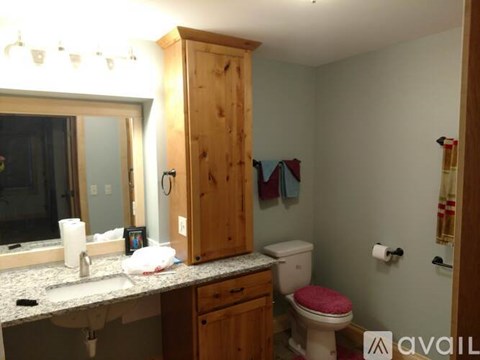 A bathroom with a wooden medicine cabinet, toilet, and sink.