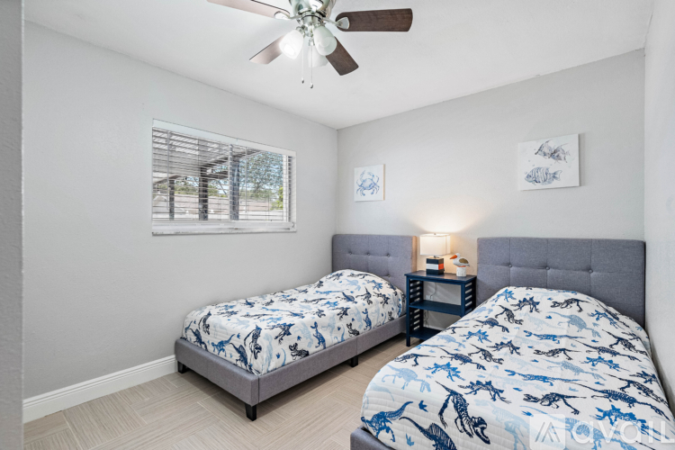 A bedroom with two beds and a ceiling fan.