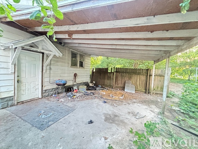 A dirty patio area with a white door and a wooden fence.