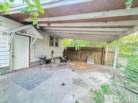 A dirty patio area with a white door and a wooden fence.