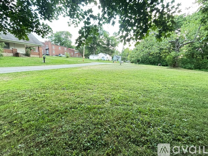 A grassy area with trees and a building in the background.