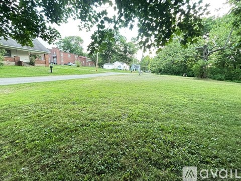 A grassy area with trees and a building in the background.