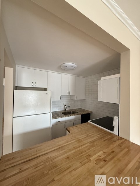 A kitchen with white cabinets and a wooden floor.