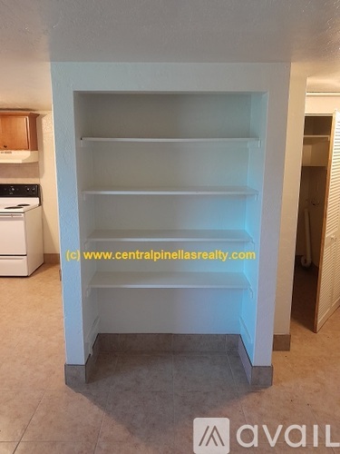 A white shelving unit in a room with a washing machine in the background.