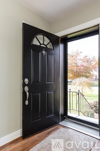 A black door with a glass window and a metal railing.