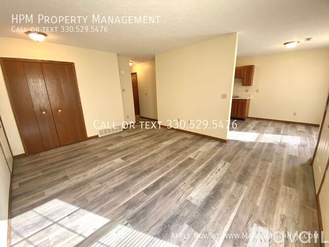 A room with wooden flooring and a door on the left side.