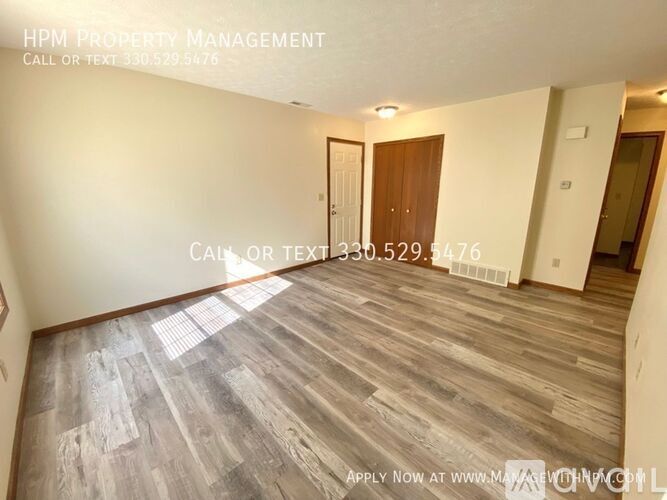 A room with wooden flooring and a door in the background.