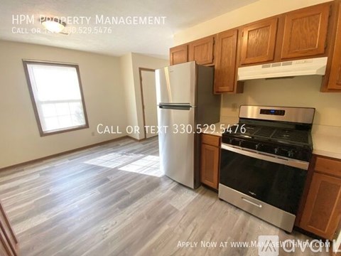A kitchen with a stainless steel refrigerator and stove, and wooden cabinets.