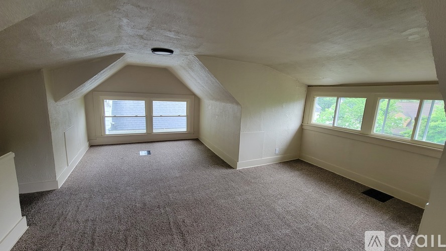 A room with a carpeted floor and a window with a view of trees.