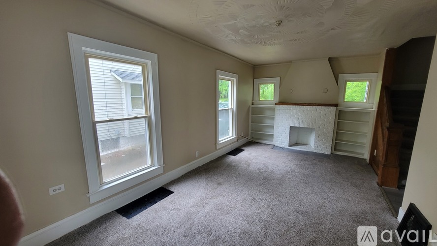 A room with a carpeted floor and a fireplace.