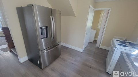 A stainless steel refrigerator with a water dispenser is in a kitchen with wood flooring.