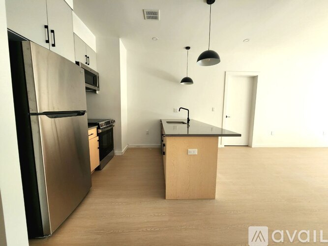 A kitchen with a refrigerator, microwave, oven, and sink.