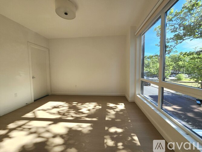 A room with a large window and a door is available for rent.