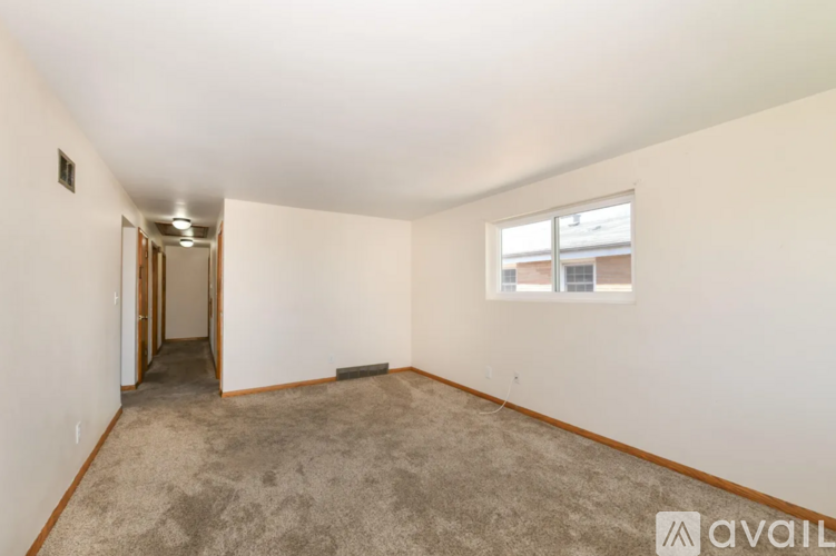 A room with a carpeted floor and a window with a view of a building outside.