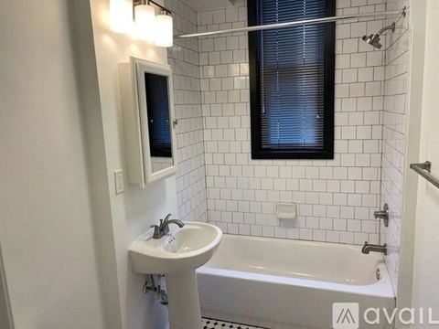A white sink is on a white countertop in a white tiled bathroom.
