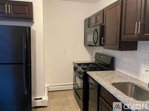 A kitchen with a black refrigerator and a black stove top oven.