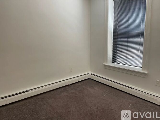 A room with a window and a carpeted floor.
