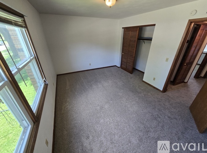 A room with a carpeted floor and a window on the left side.