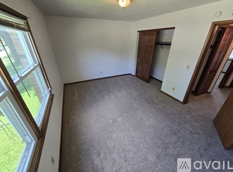 A room with a carpeted floor and a window on the left side.