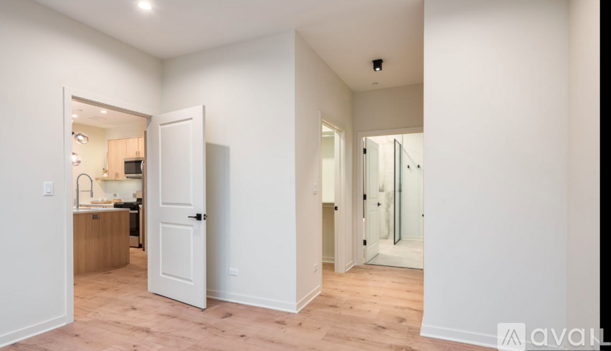 A white door opens to a kitchen with wooden floors.
