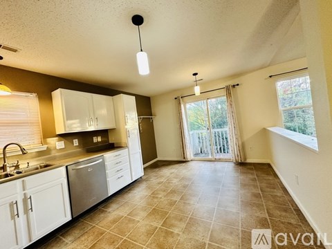 A kitchen with white cabinets and a tiled floor.
