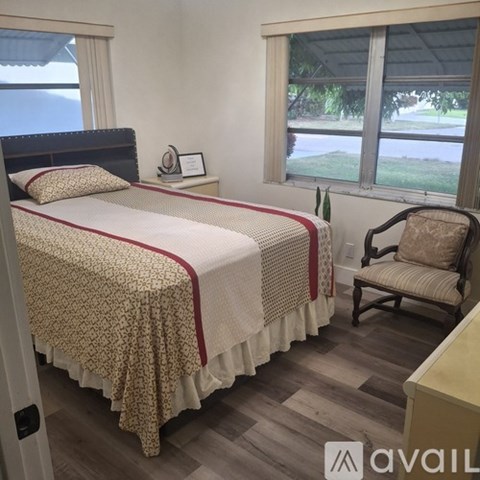 A bedroom with a large bed and a chair by the window.