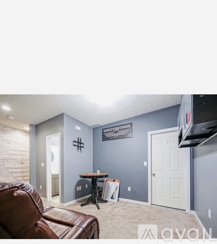 A living room with a brown leather couch and a grey wall.