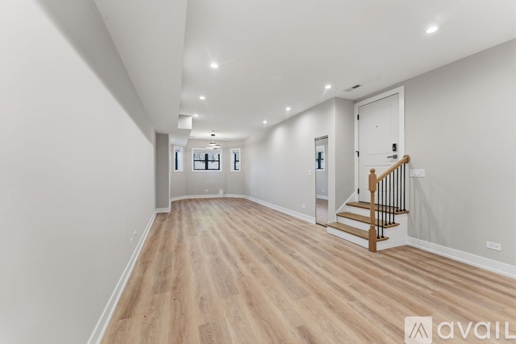 A spacious room with wooden flooring and a staircase with a wooden railing.