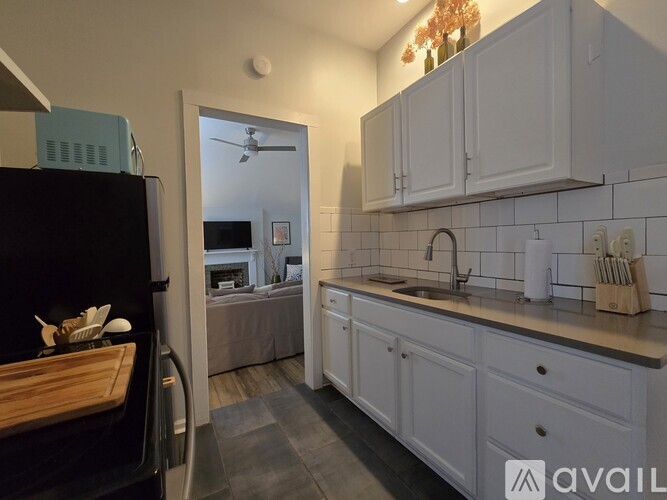 A kitchen with white cabinets and a black fridge.