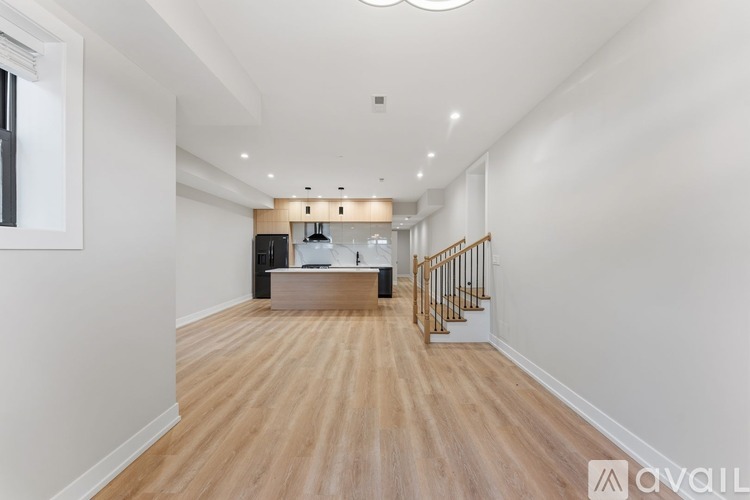 A spacious room with wooden flooring and a staircase with a metal railing.
