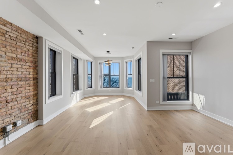 A spacious room with wooden floors and a brick wall on one side.