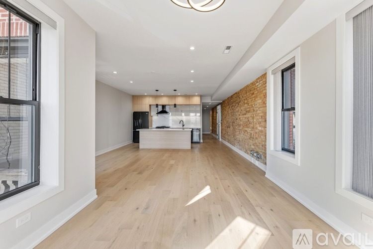 A spacious room with wooden flooring and a brick wall.