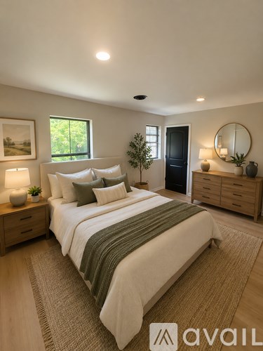 A bedroom with a large bed, a side table with a lamp, and a dresser with a mirror.