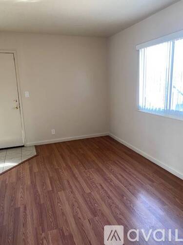 A room with wooden flooring and a window with blinds.