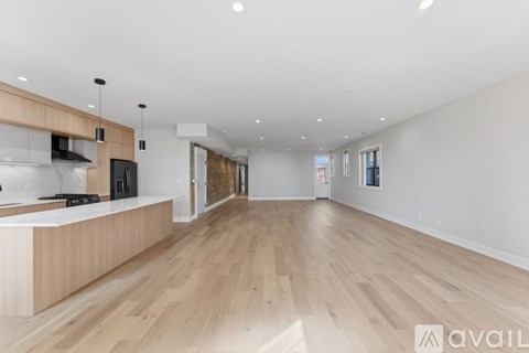 A spacious room with wooden flooring and a kitchen area with a counter and cabinets.