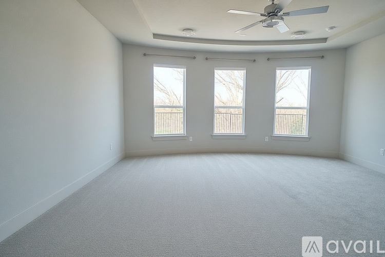 A spacious room with a ceiling fan and carpeted floor.