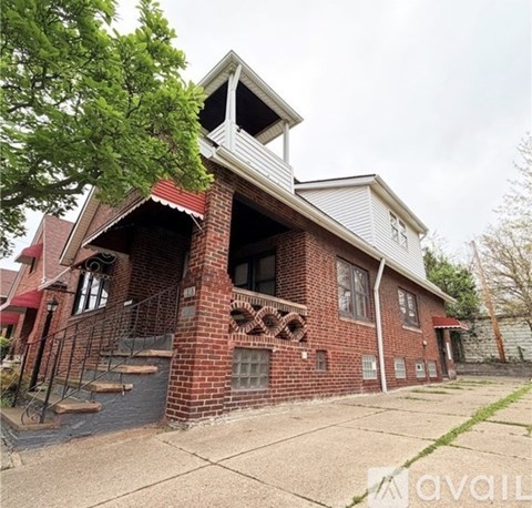 A red brick house with a white gable and a balcony.