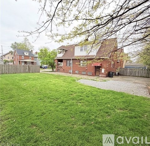 A backyard with a green lawn and a house in the background.