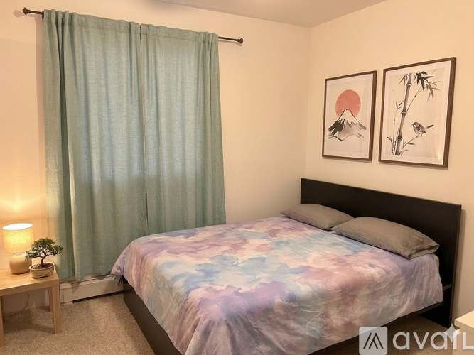 A bedroom with a bed, nightstand, and pictures on the wall.