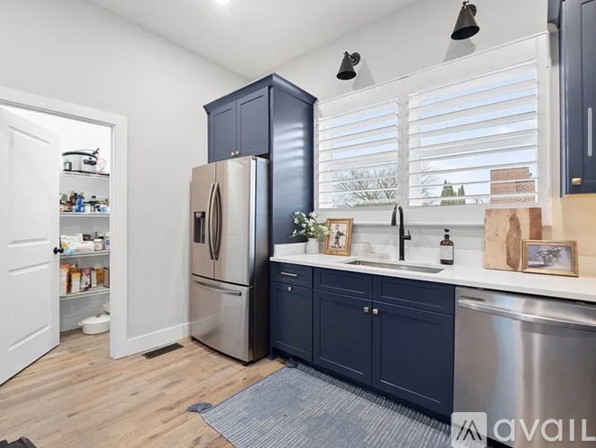 A kitchen with dark blue cabinets and a stainless steel refrigerator.