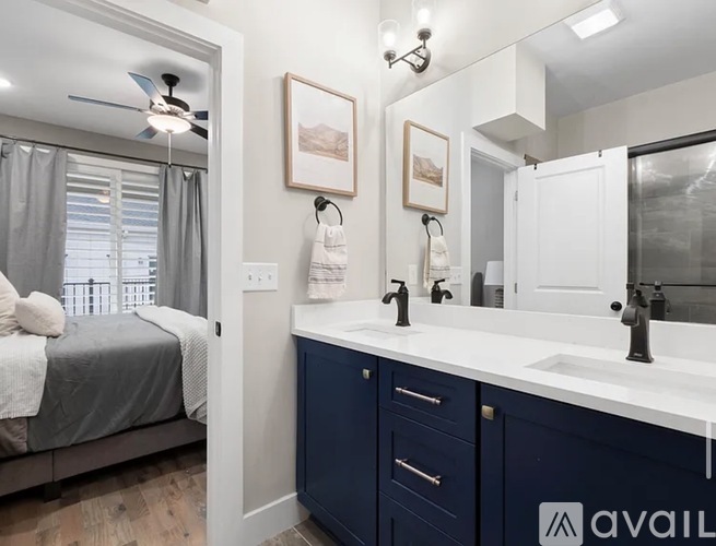 A bathroom with a bedroom area and a vanity with a mirror.